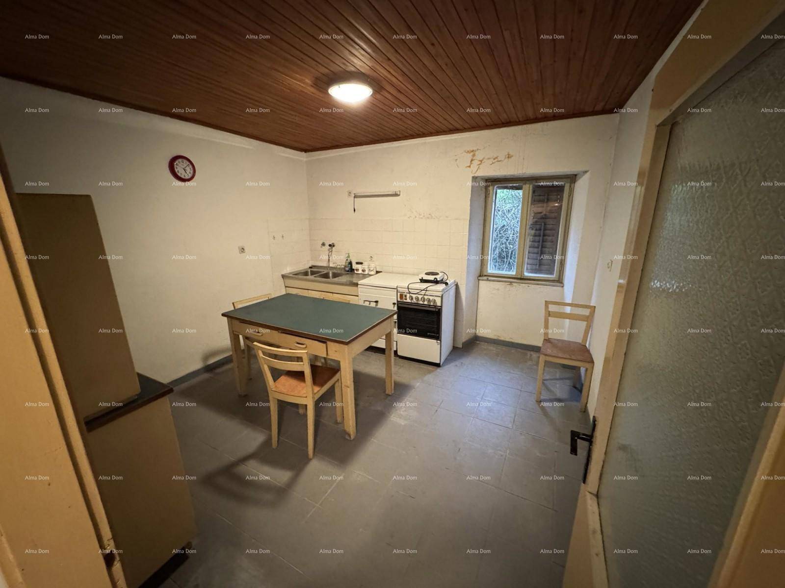 Einfache Küche mit Holztisch, Spüle und Herd unter einer rustikalen Holzdecke.