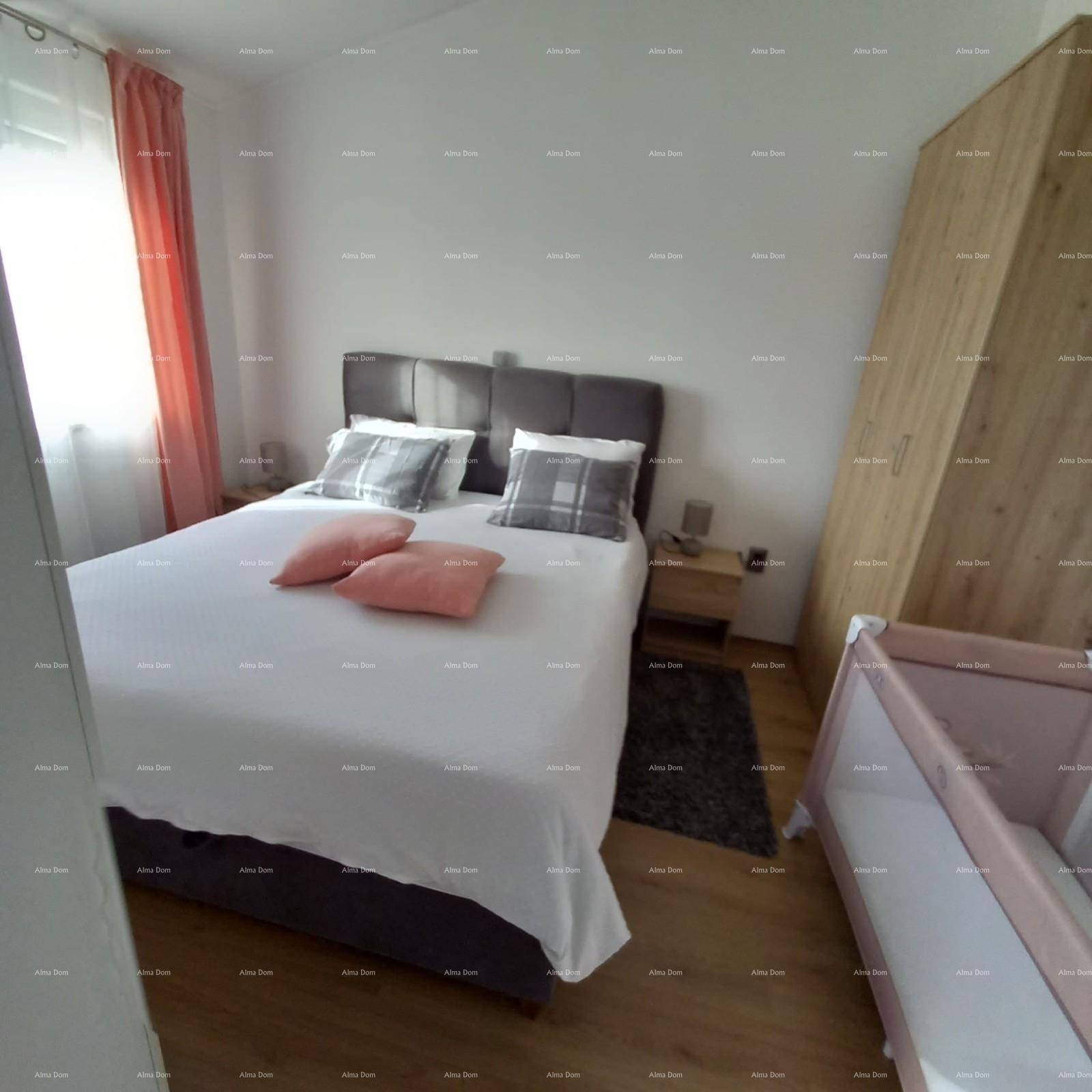 Schlafzimmer mit Doppelbett, Nachttischen und einem Kinderbettchen im Vordergrund.