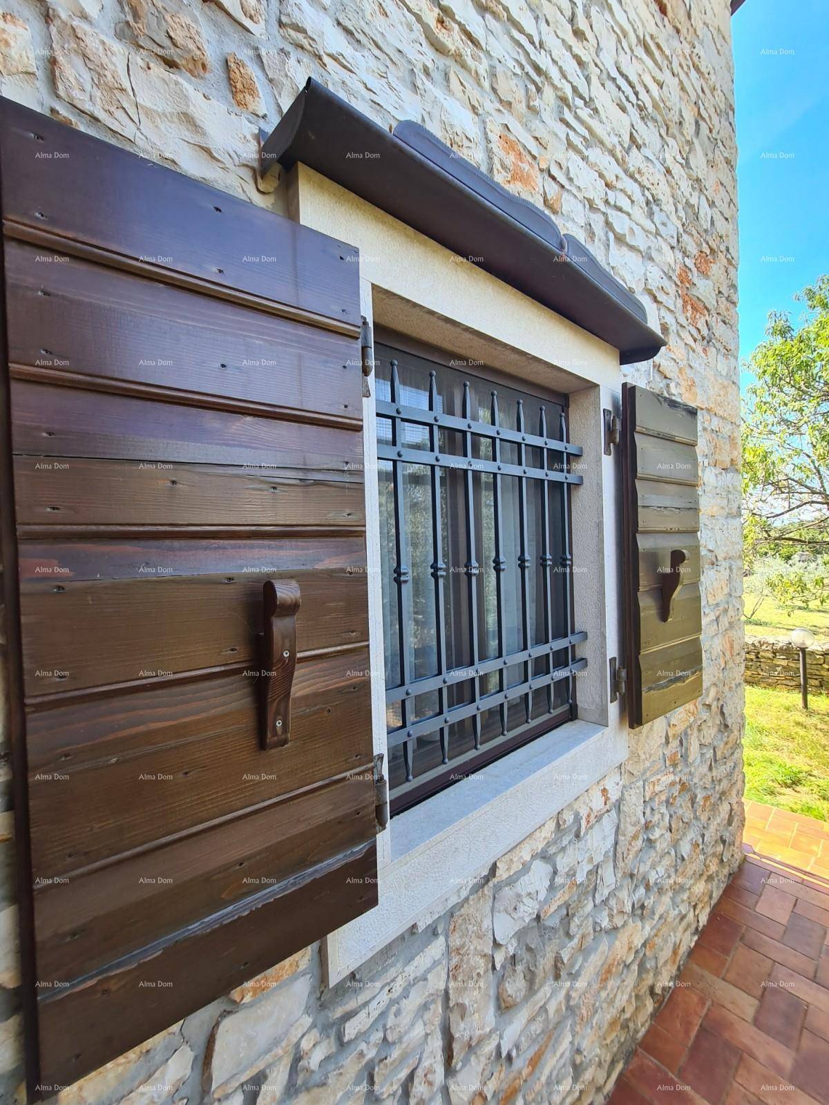 Detailansicht eines Fensters mit rustikalen Holzfensterläden und schmiedeeisernen Gittern in einer Steinwand.