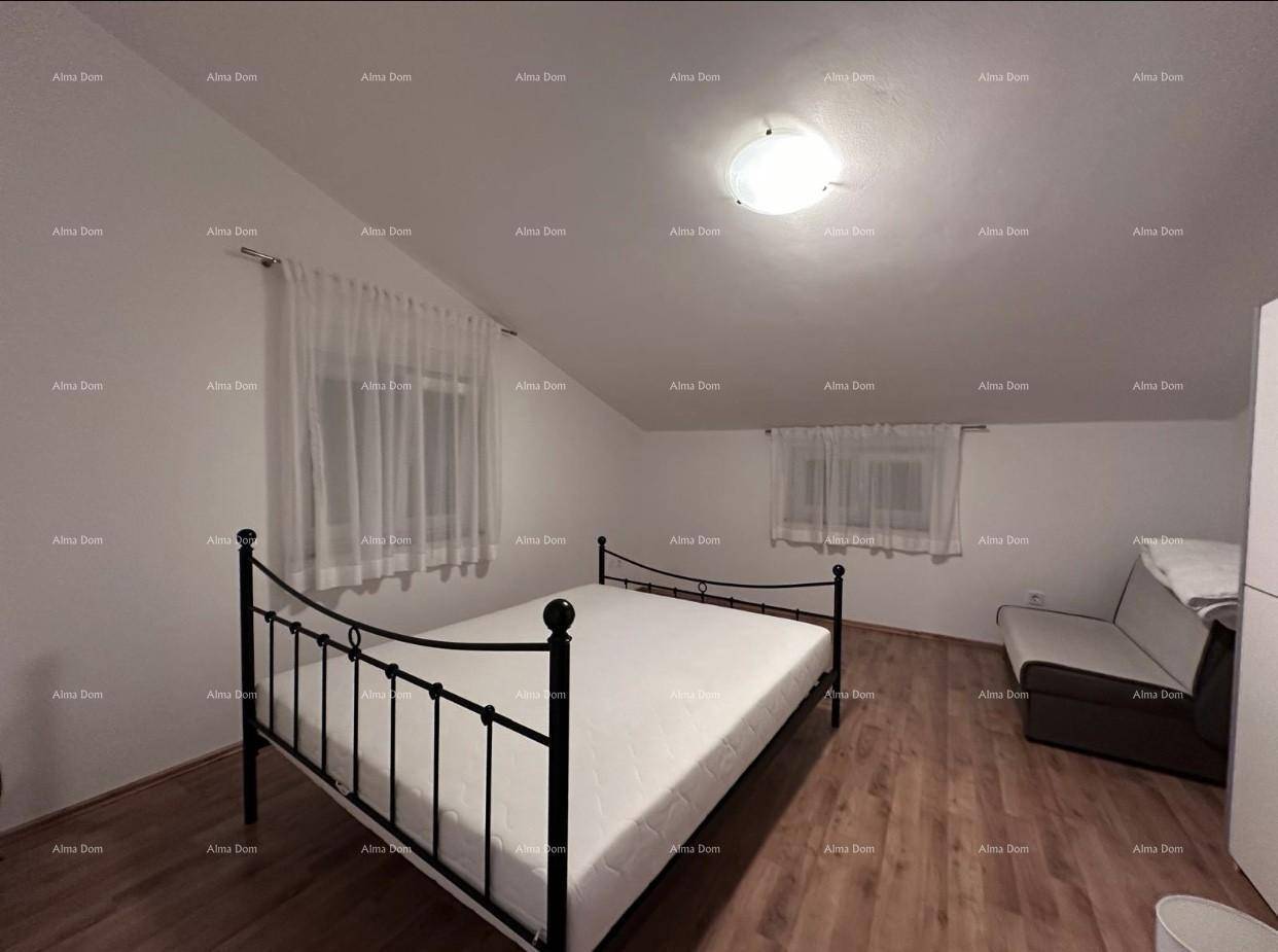 Gemütliches Schlafzimmer im Dachgeschoss mit Metallbett, Sofa und schrägen Decken.