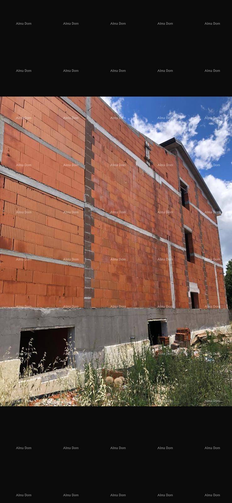 Seitenansicht des im Bau befindlichen Gebäudes mit Ziegelmauerwerk und Fensteröffnungen unter blauem Himmel.