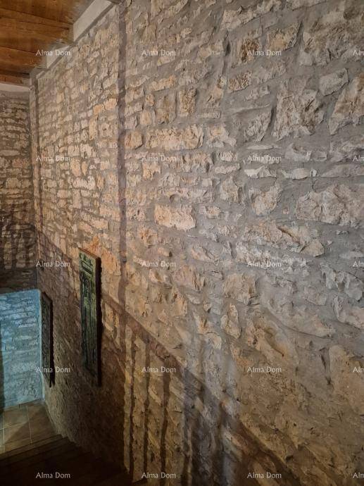 Treppenhaus mit rustikaler Steinwand und gefliesten Stufen, die nach oben führen.