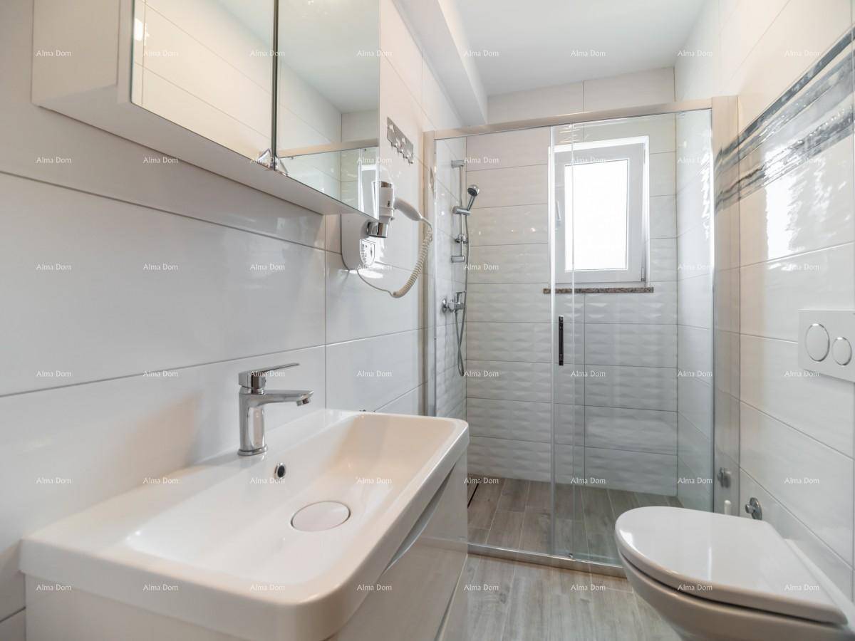 Modernes Badezimmer mit weißen Fliesen, Einzelwaschbecken, Toilette und begehbarer Dusche mit Glaswand.