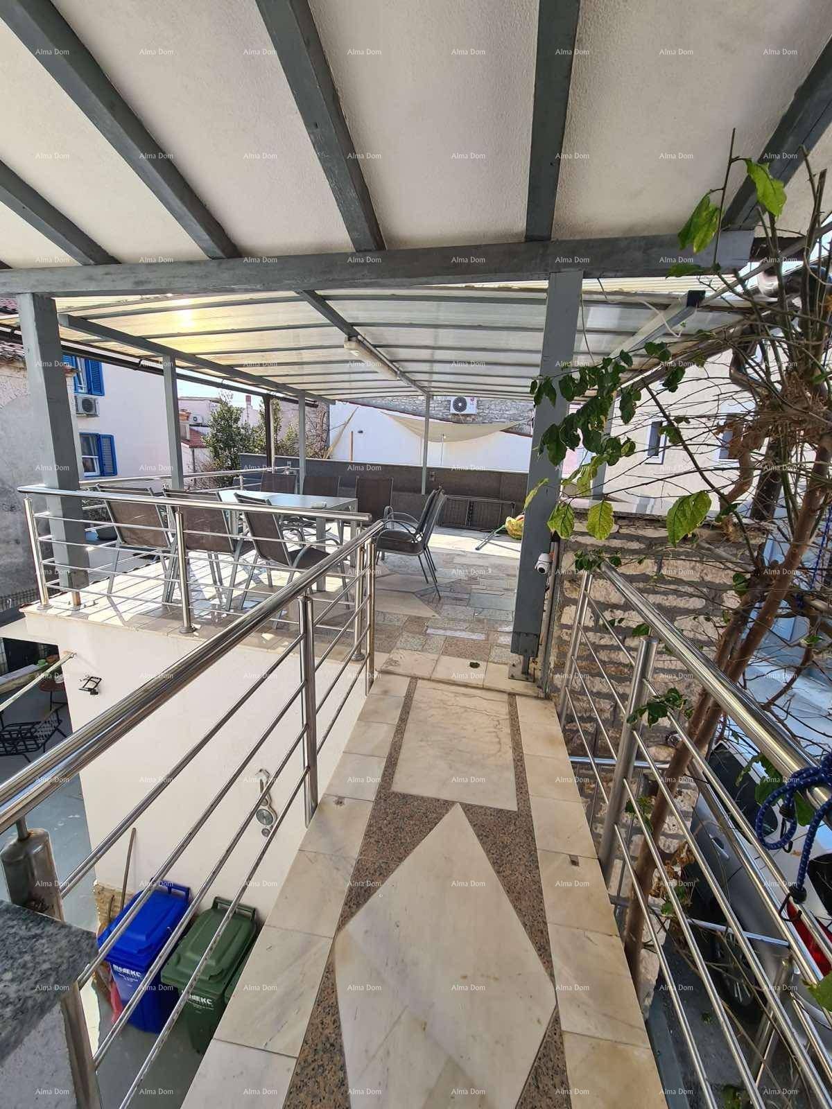 Balkon mit Metallgeländer und Blick auf die überdachte Terrasse und die Umgebung.