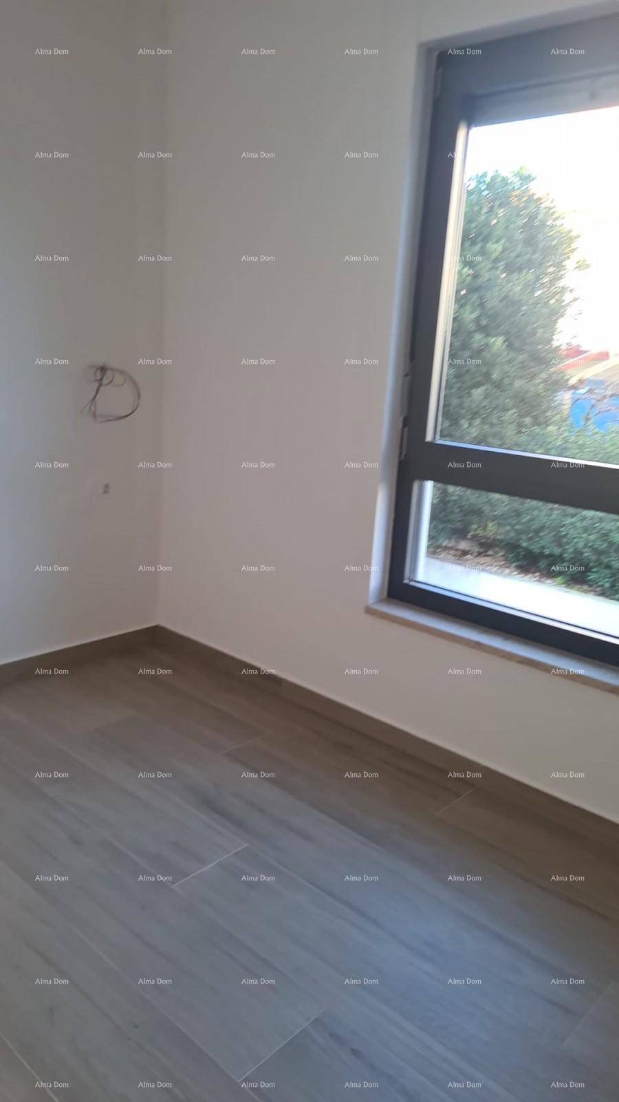 Helles Zimmer mit Holzboden und Fenster, das einen Blick ins Grüne bietet.