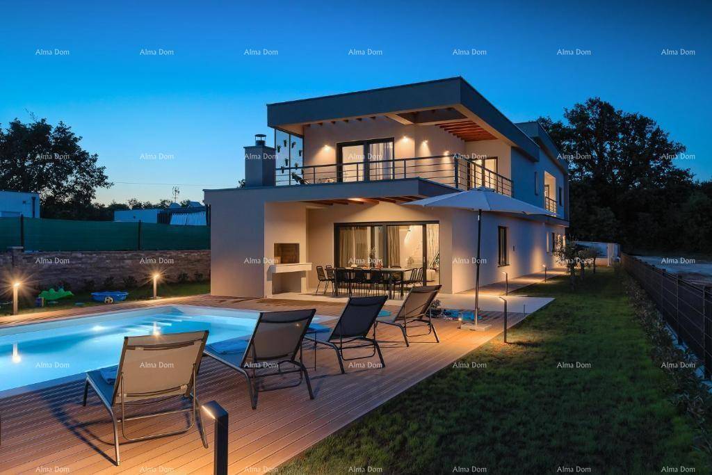 Beleuchtete moderne Villa mit Pool und Terrasse bei Sonnenuntergang, umgeben von Grünflächen.
