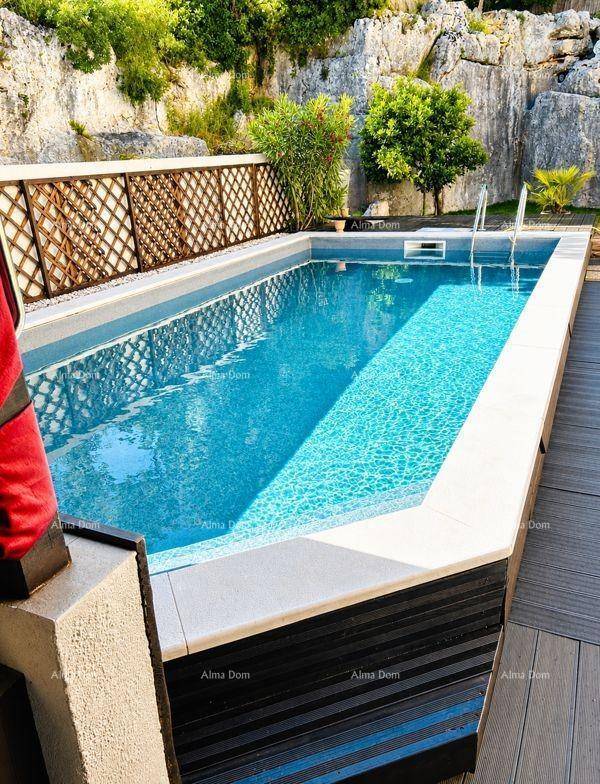 Detailansicht des Pools mit Holzdeck und natürlicher Felswand im Hintergrund, umgeben von Grün.