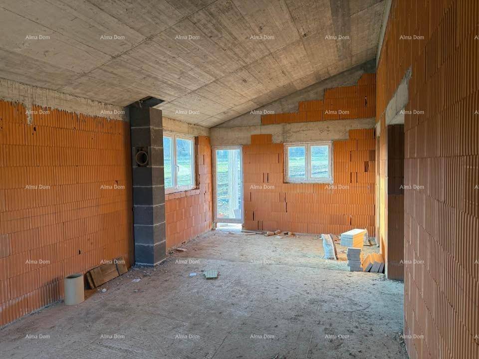 Innenraum im Rohbau mit Ziegelwänden, Betonboden und Fenstern, die viel Tageslicht hereinlassen.