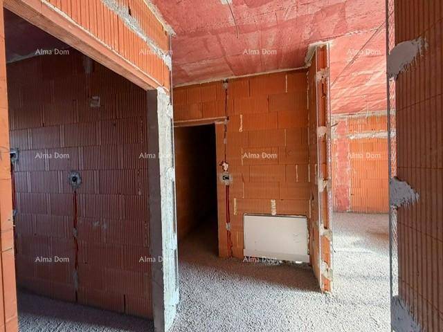 Rohbau eines Flurbereichs mit sichtbaren Ziegelwänden und Türöffnungen.
