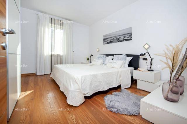 Modernes Schlafzimmer mit Holzboden, weißer Einrichtung und viel Tageslicht.