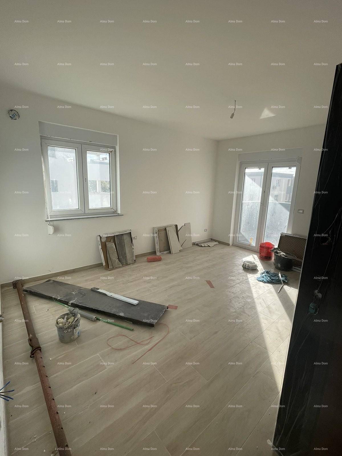 Helles Wohnzimmer im Rohbau mit Fliesenboden, großen Fenstern und Zugang zum Balkon.
