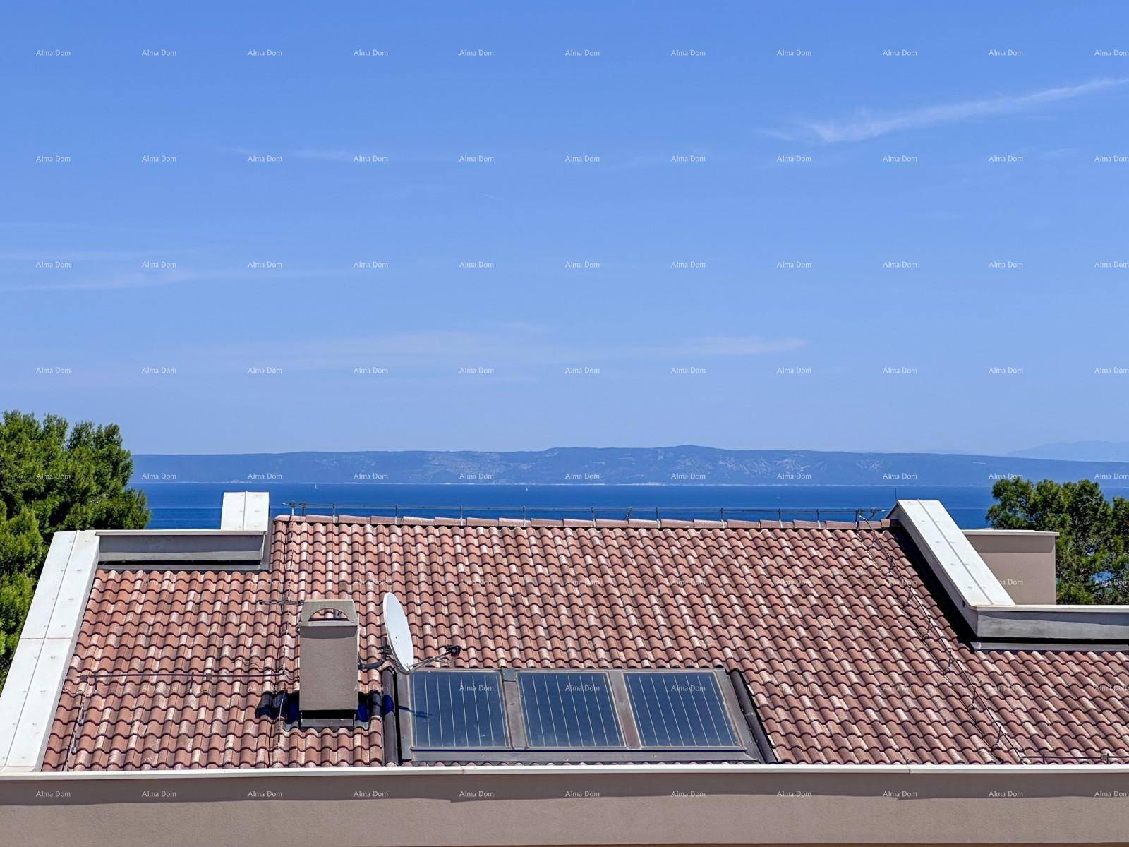 Detailansicht eines Ziegeldachs mit Solarmodulen und weitem Blick auf das Meer.