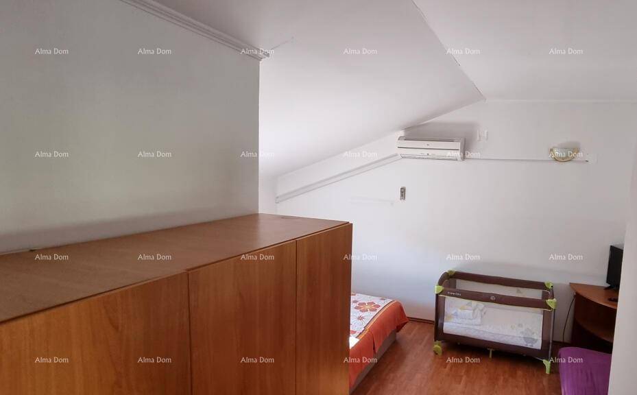 Dachschlafzimmer mit Schrank, Babybett und Klimaanlage unter der Dachschräge.