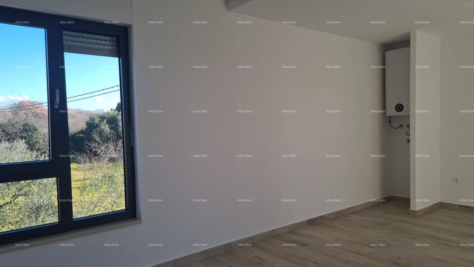 Heller Raum mit Holzboden, Fenster und einem an der Wand montierten Warmwasserbereiter.