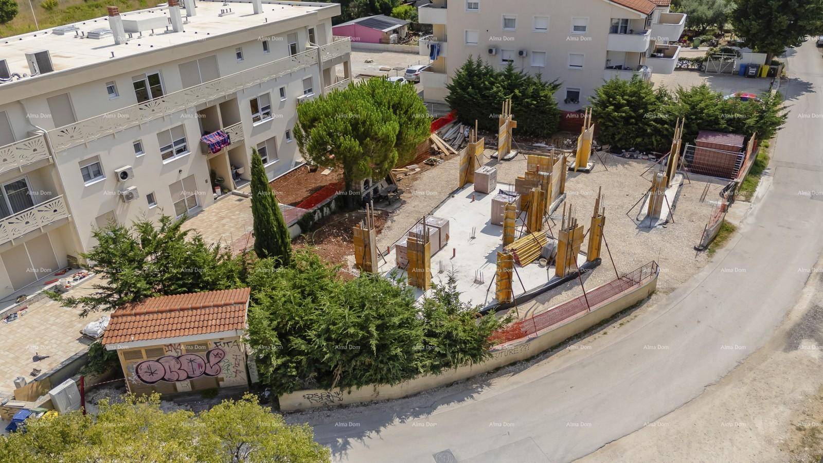 Übersicht der Baustelle mit Fundamentarbeiten, einem bestehenden Gebäude und einem kleinen Nebengebäude.