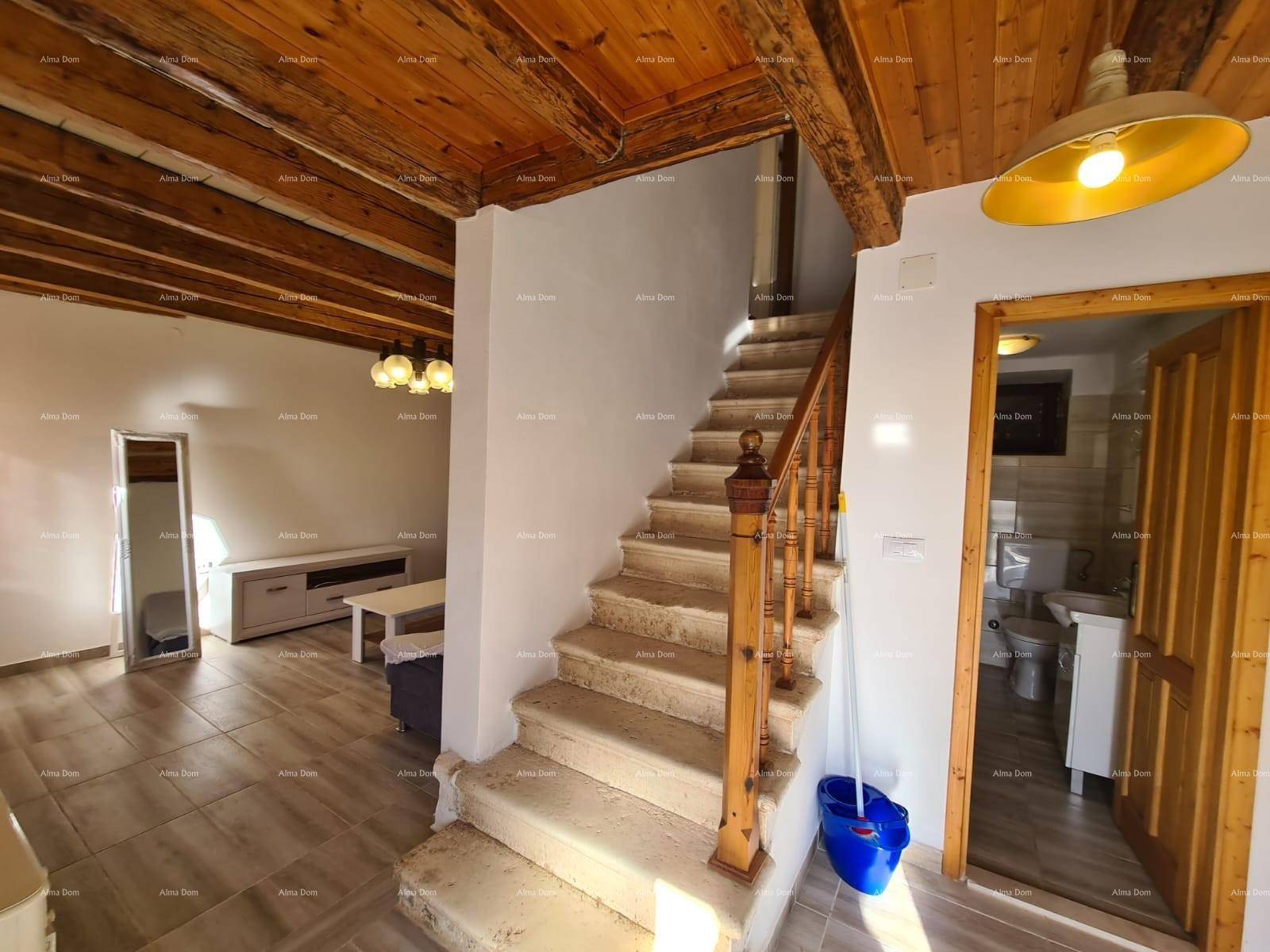 Steintreppe verbindet Wohnbereich und Badezimmer, unter rustikaler Holzbalkendecke.