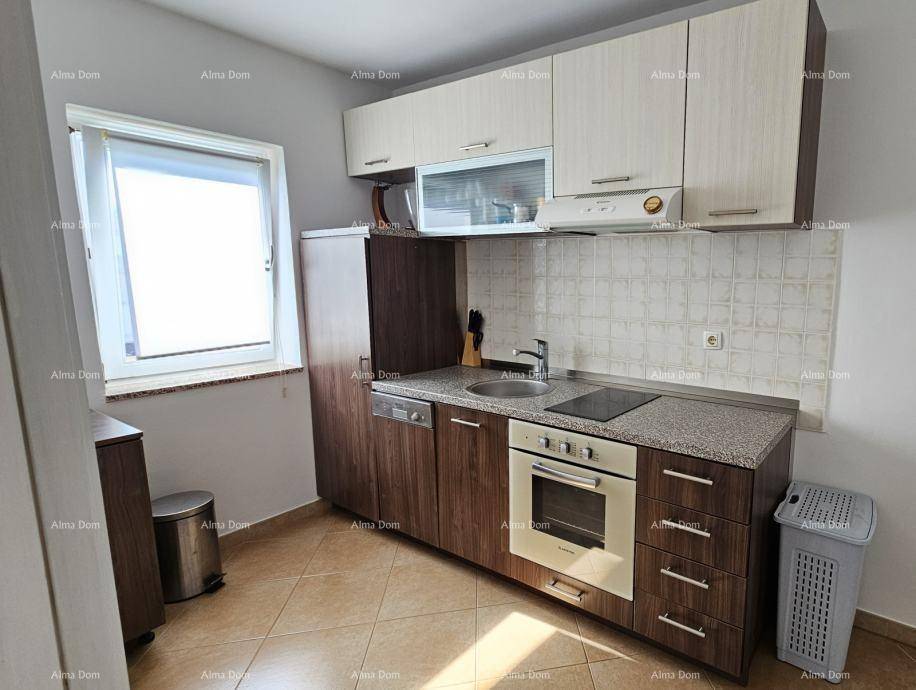 Funktionale Küche mit Holzschränken, Einbaugeräten und einem Fenster für Tageslicht.