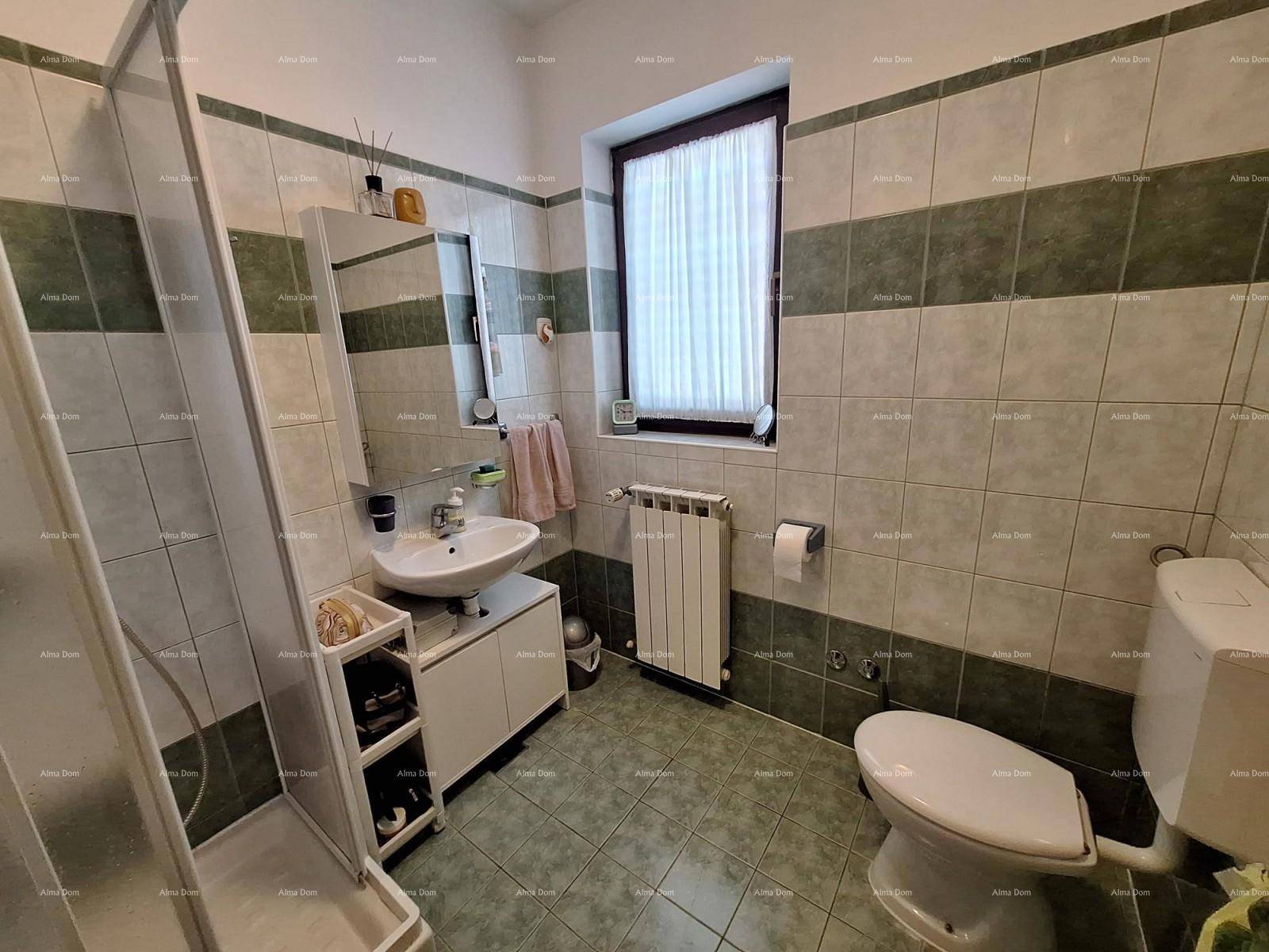 Badezimmer mit Duschkabine, Waschbecken und grün-weiß gefliesten Wänden.