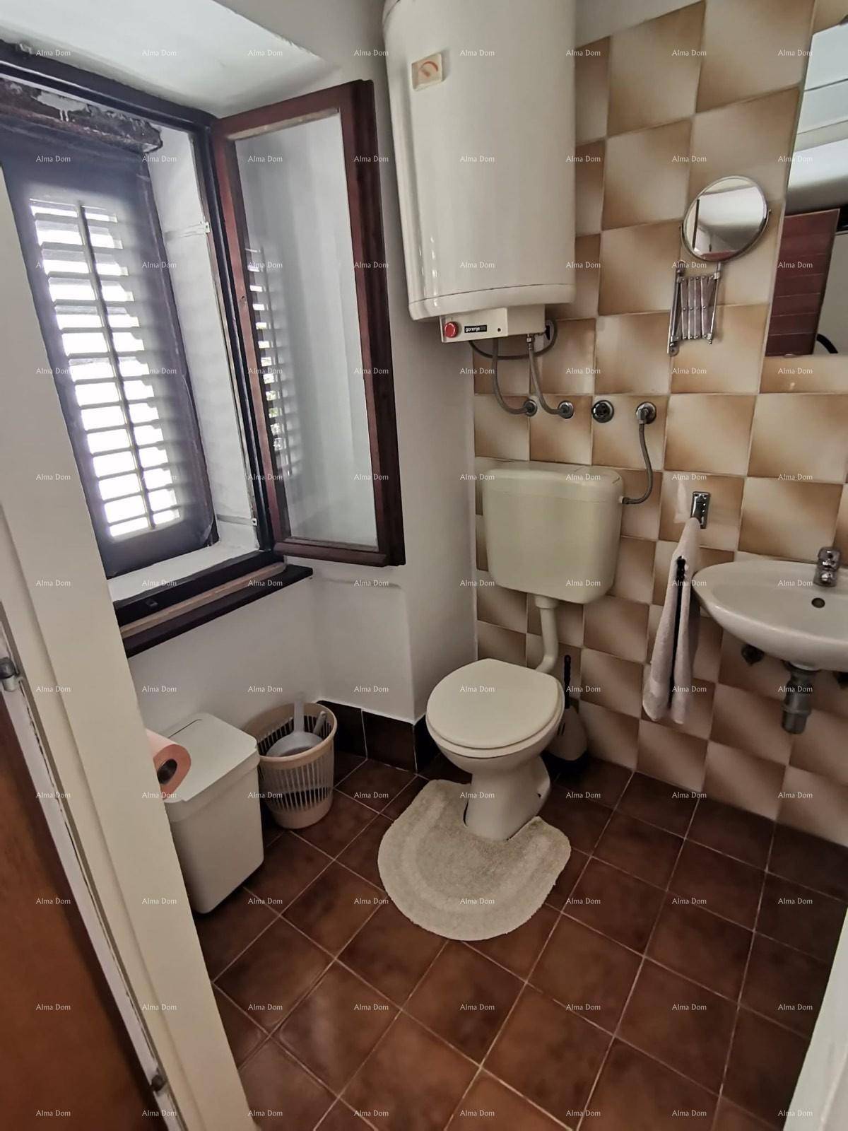 Badezimmer mit Fenster, Toilette, Waschbecken und Boiler, gefliest in Brauntönen.