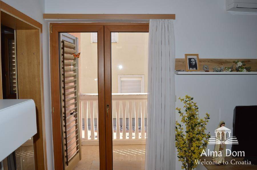 Wohnzimmer mit Balkonzugang und Fensterläden, das viel Tageslicht hereinlässt.