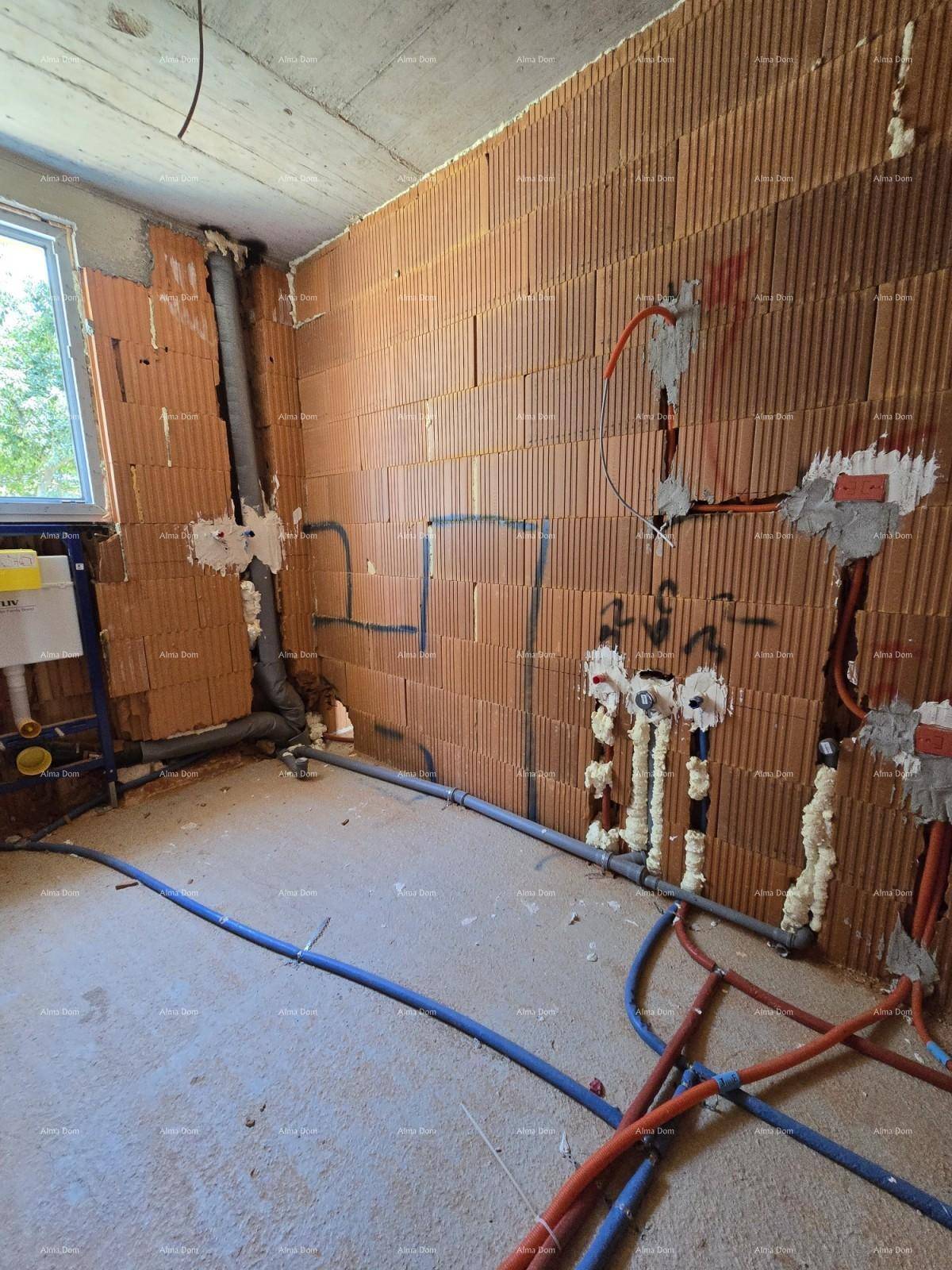 Rohbau-Badezimmer mit unverputzten Ziegelwänden, Fenster und vorbereiteten Sanitärinstallationen für WC und Waschbecken.