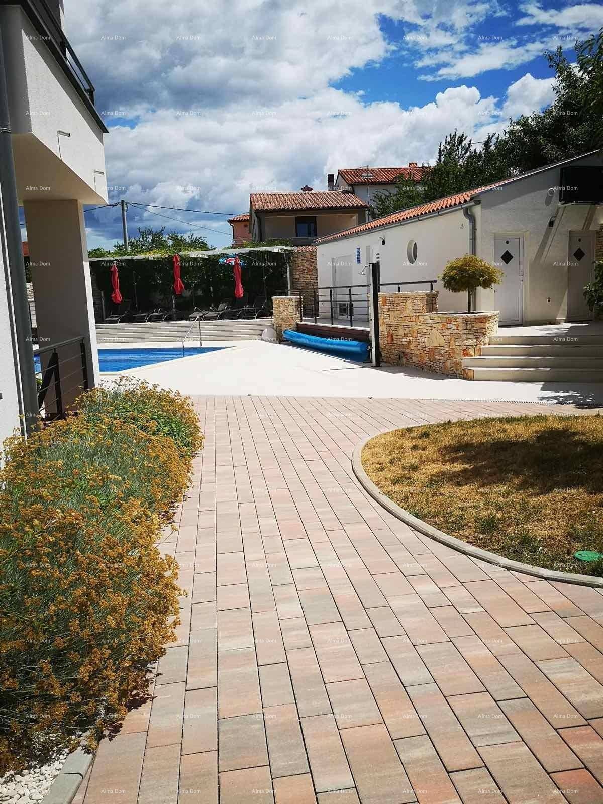 Heller Außenbereich mit gepflastertem Weg, grünen Sträuchern und Blick auf den Poolbereich.