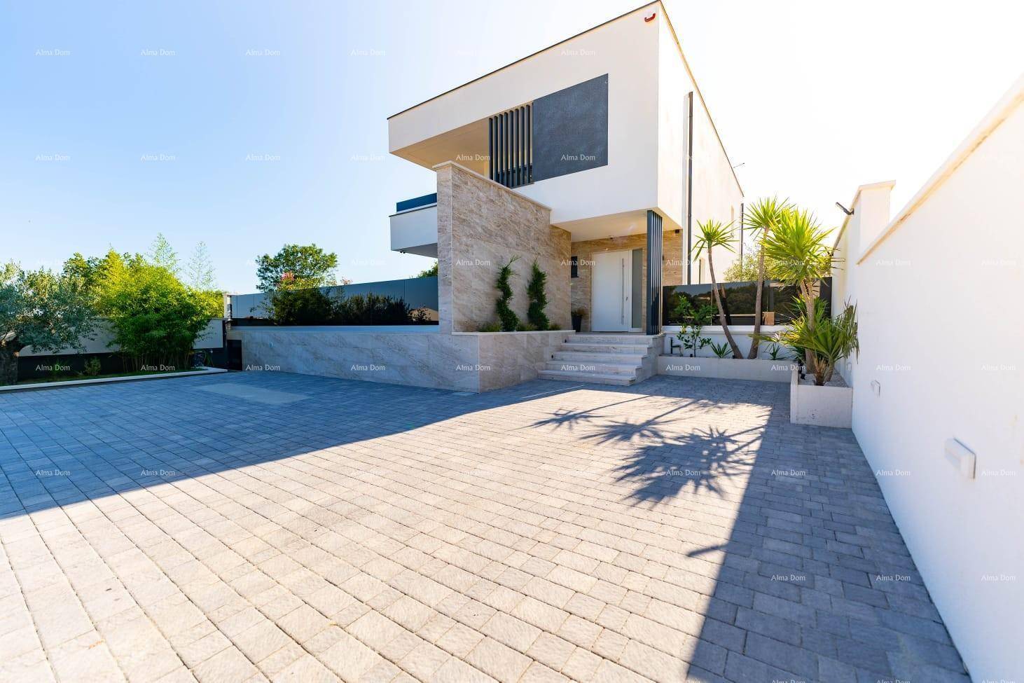 Moderne Villa mit heller Fassade, gepflasterter Auffahrt und mediterraner Bepflanzung.