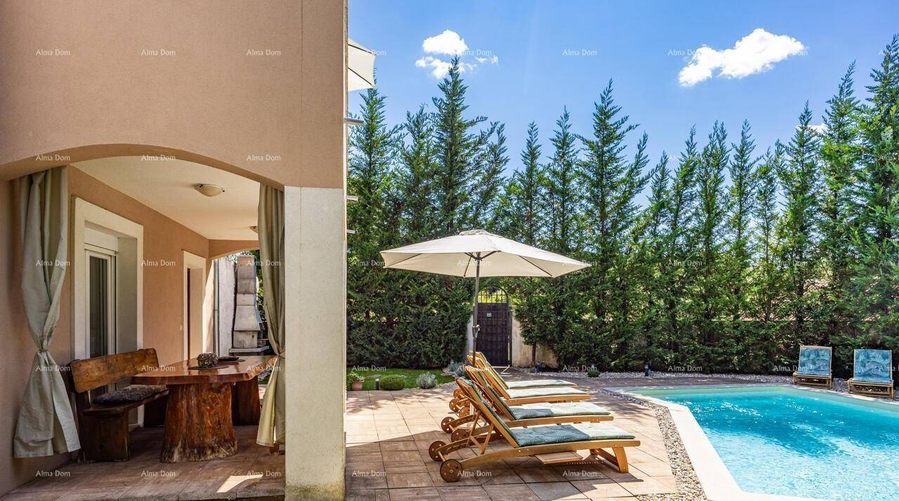 Überdachte Terrasse mit rustikalem Esstisch und Blick auf den Poolbereich mit Sonnenliegen und grüner Hecke.