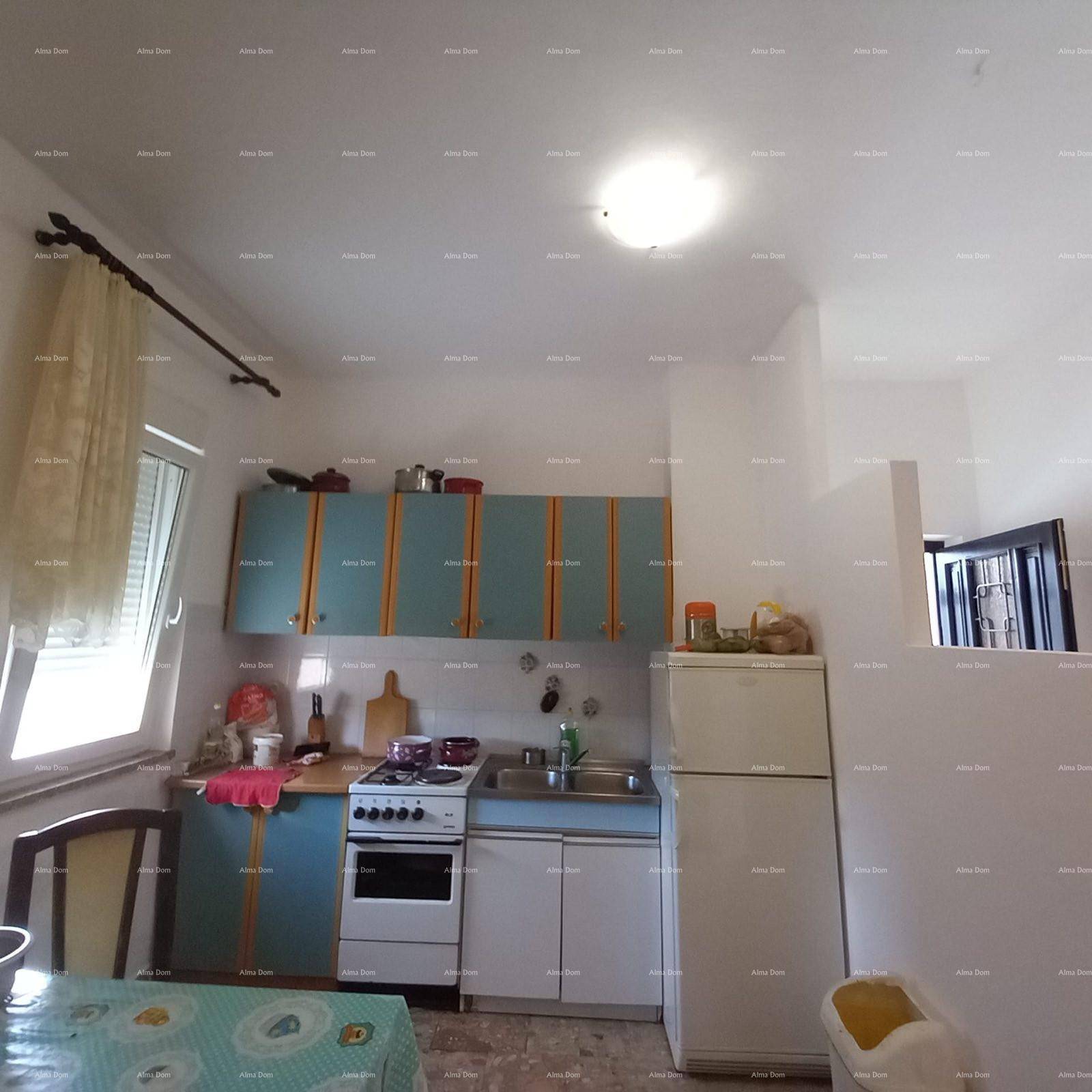Küche mit blauen und gelben Schränken, Herd und Kühlschrank, ausgestattet mit einem Fenster.