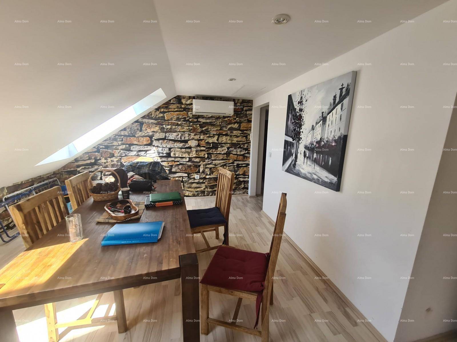 Gemütlicher Essbereich im Dachgeschoss mit rustikaler Steinwand, Holztisch und Dachfenster.