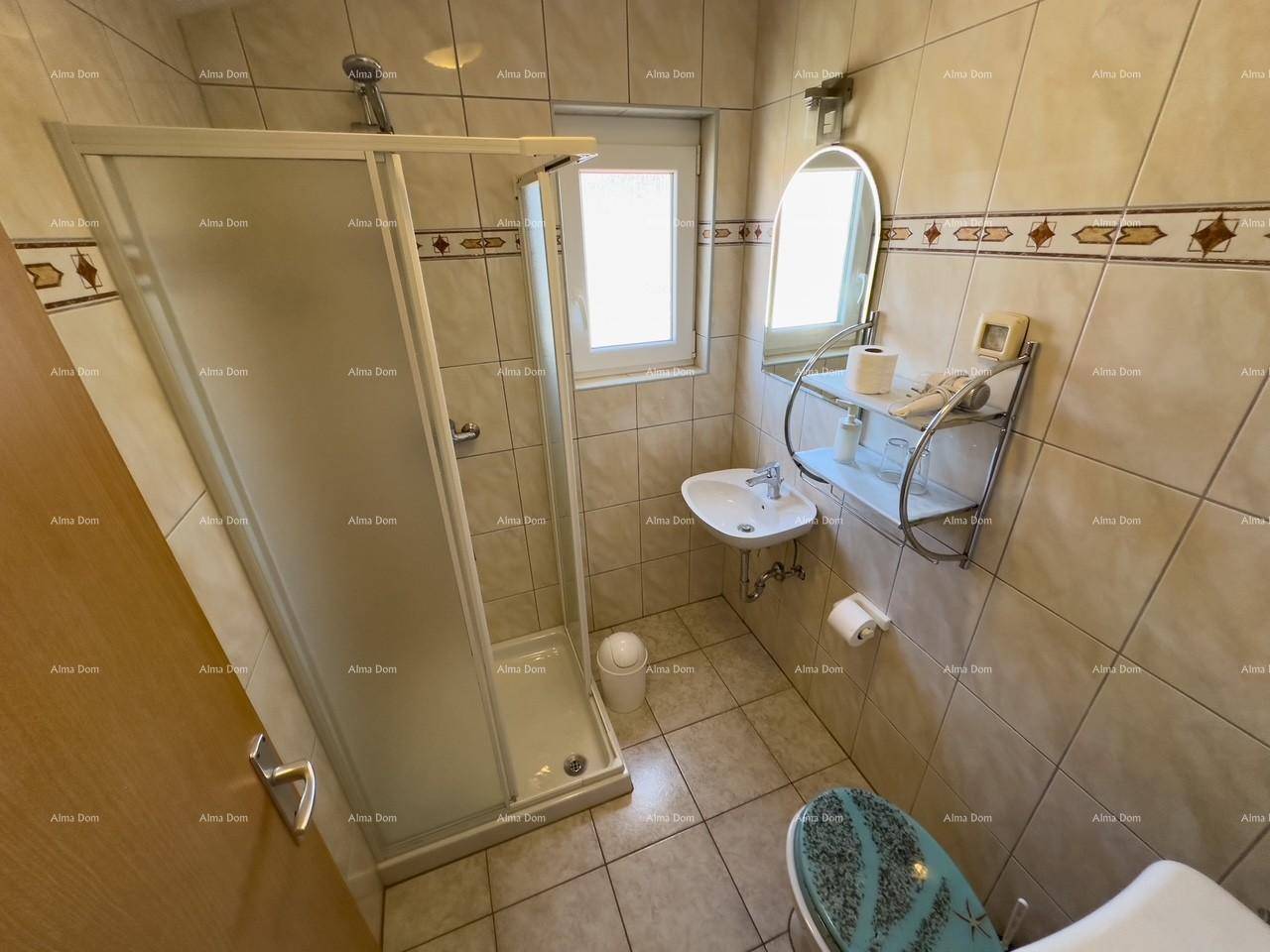 Kleines Badezimmer mit Duschkabine, WC und Fenster, komplett gefliest.