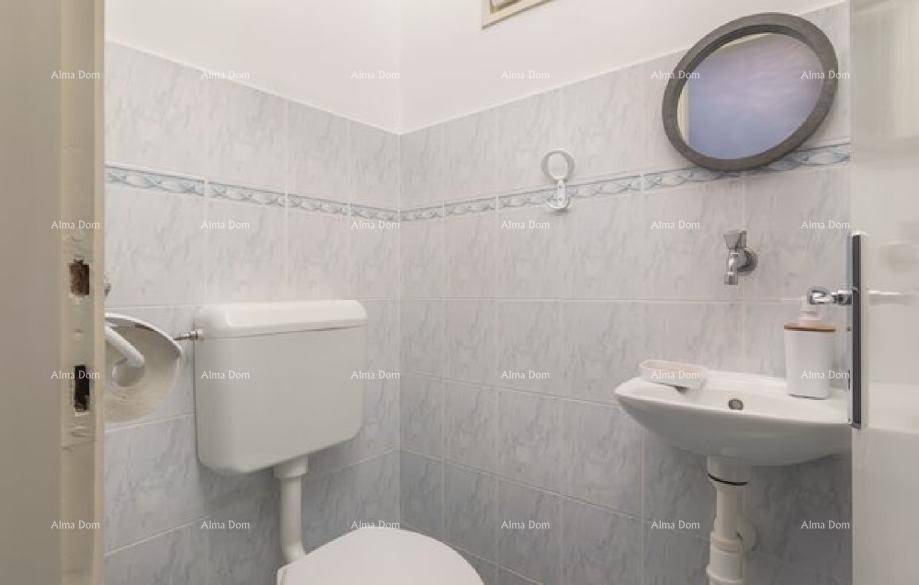 Kleines Gäste-WC mit Toilette, Waschbecken und runden Spiegel, komplett gefliest.