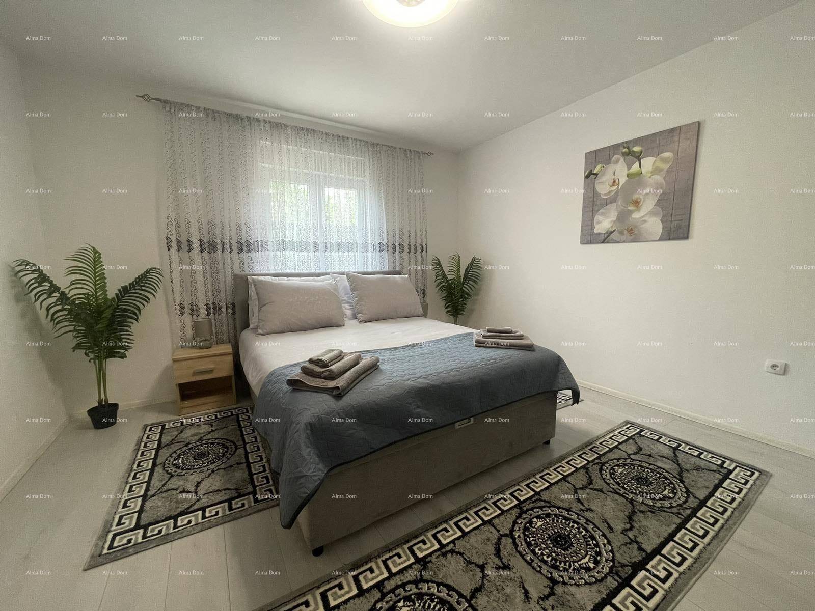Helles Schlafzimmer mit Doppelbett, Nachttischen, Laminatboden und einem Fenster mit Vorhängen.