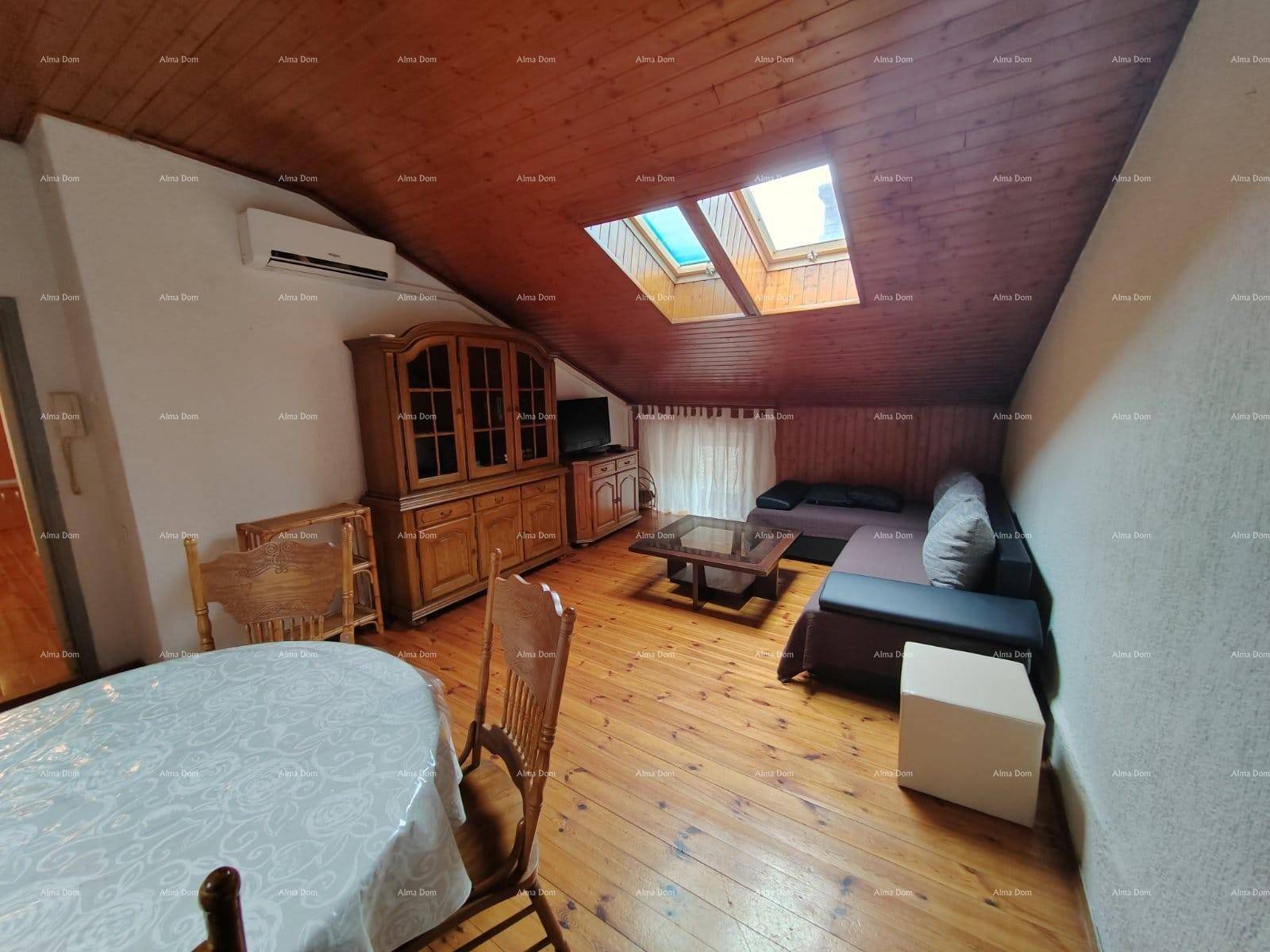 Geräumiger Wohn- und Essbereich im Dachgeschoss mit Holzboden, Sofa, Esstisch und Dachfenstern.