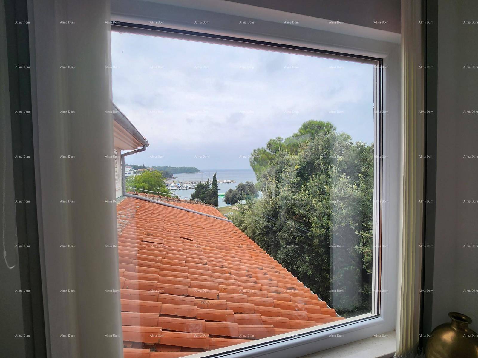 Fensterblick auf ein rotes Ziegeldach, üppiges Grün und das glitzernde Meer in der Ferne.