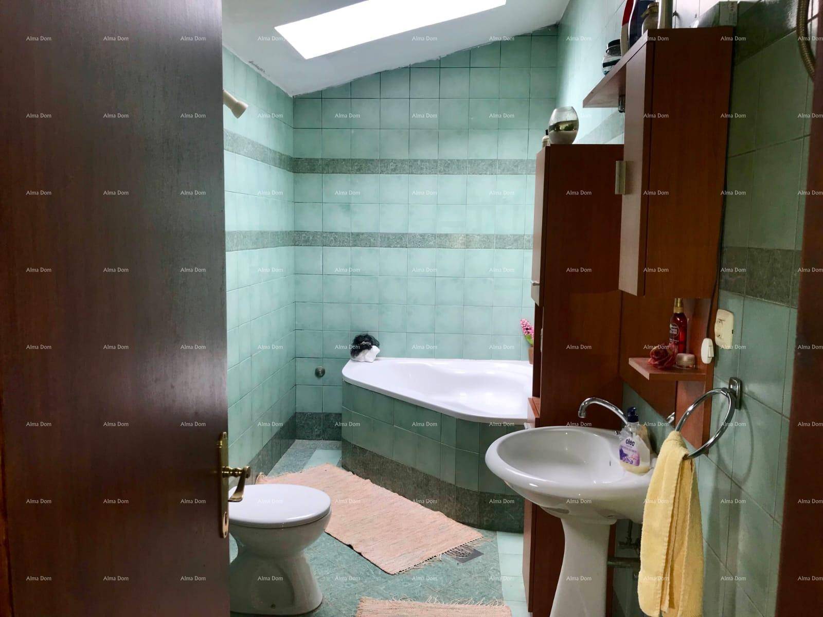 Badezimmer mit Eckbadewanne, Waschbecken und hellgrünen Fliesen.