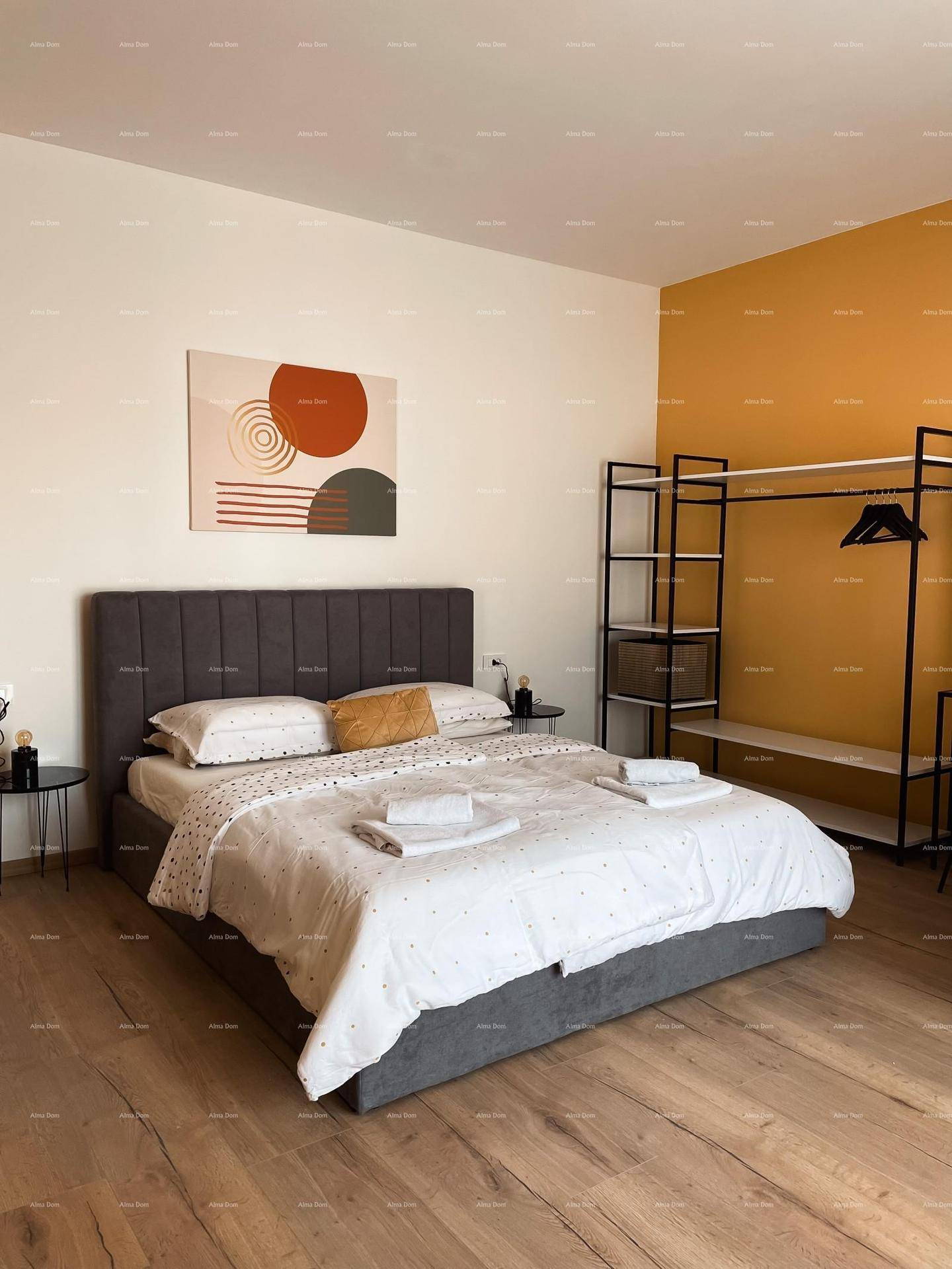 Helles Schlafzimmer mit Holzboden, bequemen Doppelbett und moderner Kunst an der Wand.