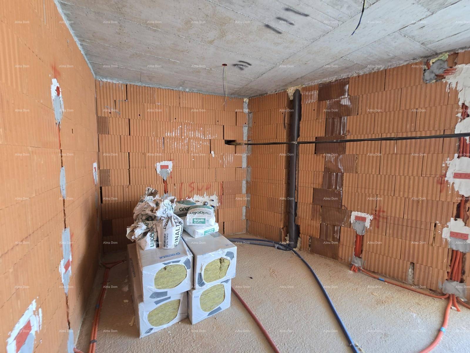 Rohbau-Innenraum mit Ziegelwänden, Betonboden, sichtbaren Installationen und gelagerten Dämmmaterialien.