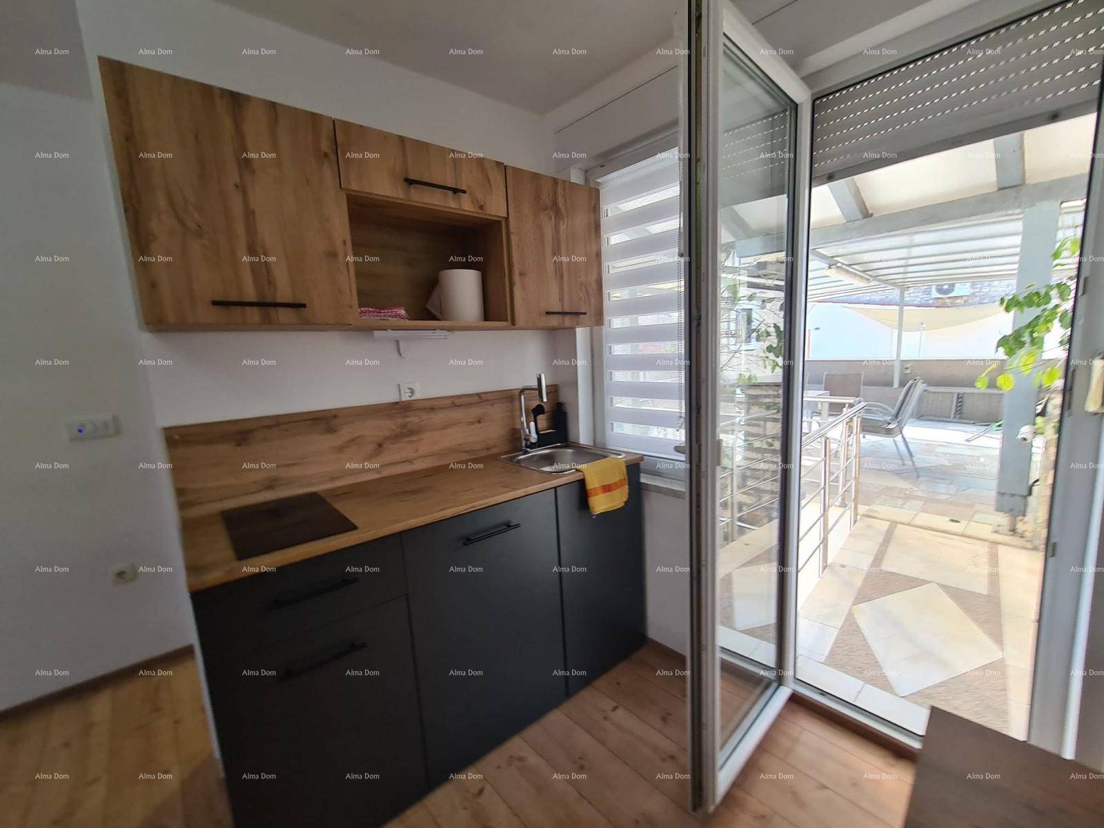 Kleine Küchenzeile mit Holzschränken und Spüle, mit Zugang zu einer überdachten Terrasse.