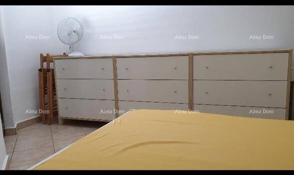 Schlafzimmer mit einem langen Sideboard und einem Ventilator, der auf dem Boden steht.