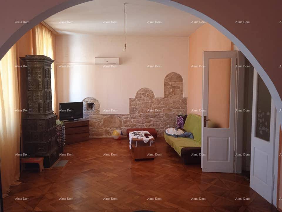 Gemütliches Wohnzimmer mit traditionellem Kachelofen, Parkettboden und rustikalen Steinakzenten an der Wand.