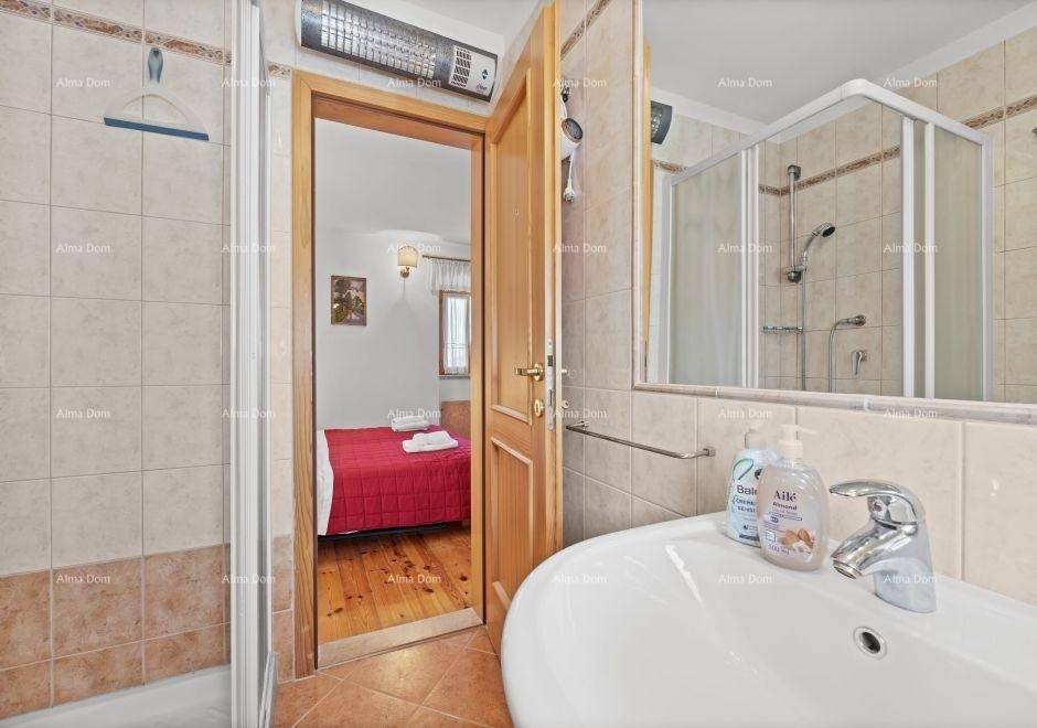Badezimmer mit Dusche, Waschbecken und Blick in das angrenzende Schlafzimmer.