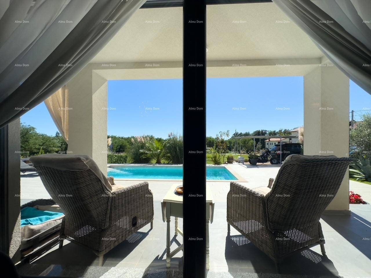 Blick vom Innenraum auf die überdachte Terrasse mit bequemen Korbsesseln und Poolblick.