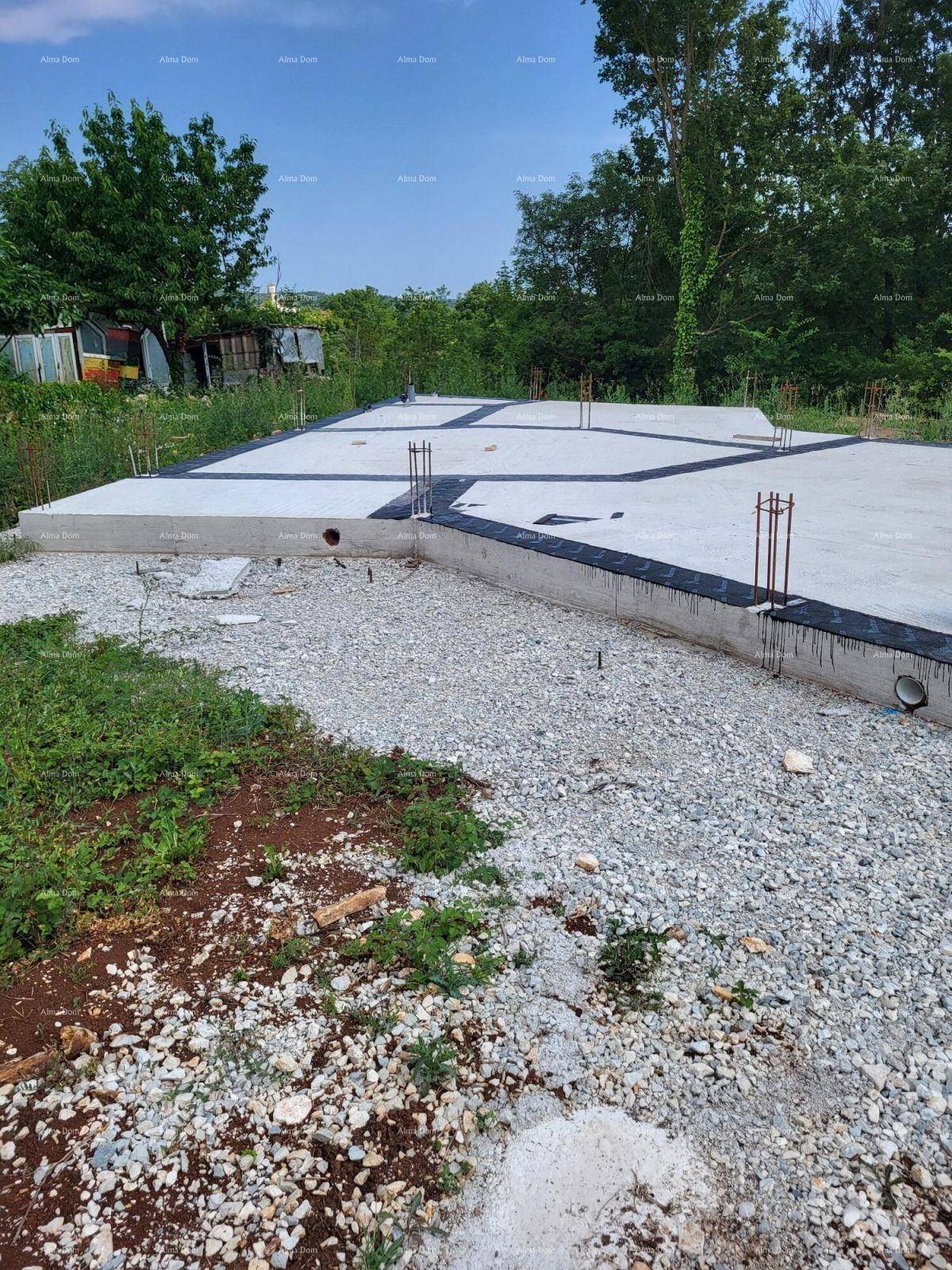 Übersicht über das Betonfundament einer zukünftigen Immobilie, umgeben von Schotter und Vegetation.