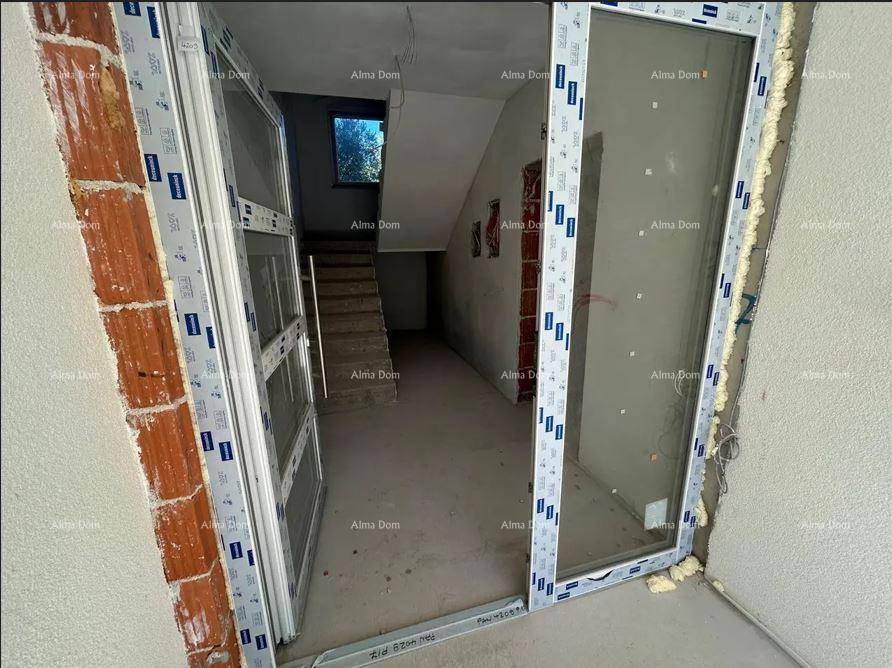Eingangsbereich mit großer Glastür und Treppe, die in die oberen Stockwerke des unfertigen Hauses führt.