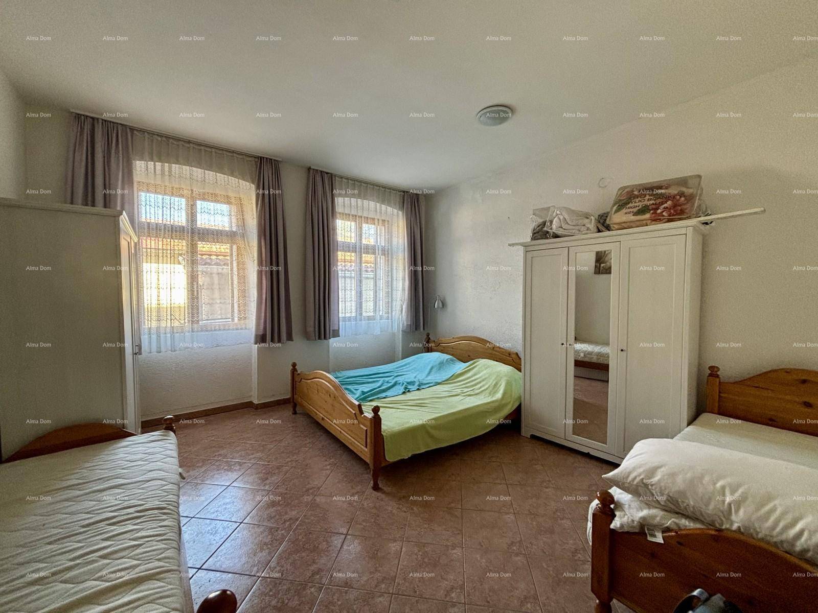 Großes Schlafzimmer mit drei Einzelbetten, einem Kleiderschrank und Fenstern, die den Raum erhellen.
