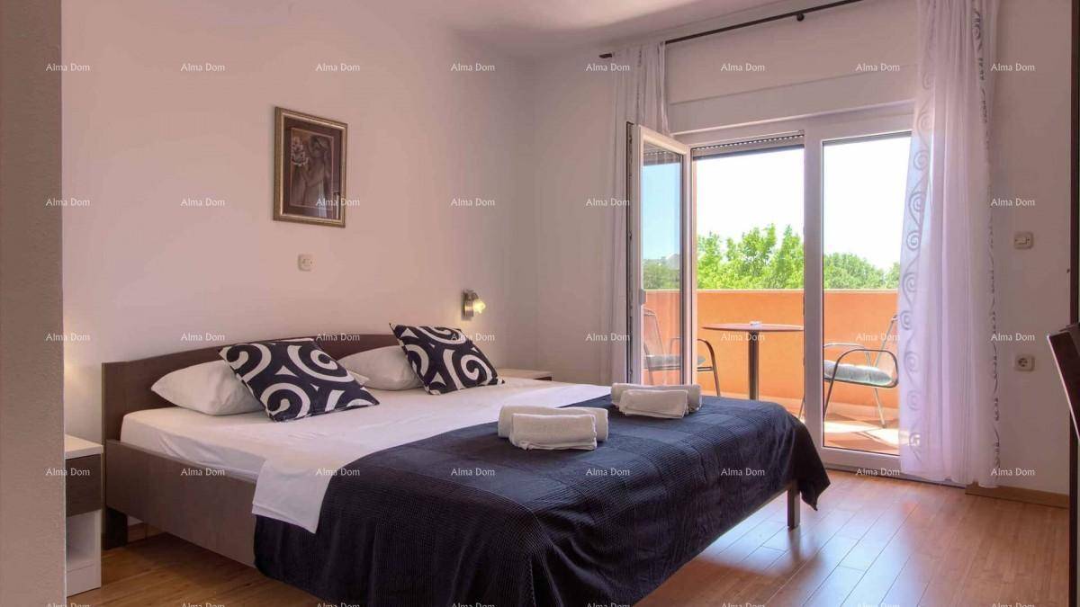 Schlafzimmer mit Doppelbett, Holzboden und Zugang zu einem Balkon mit Sitzgelegenheiten.