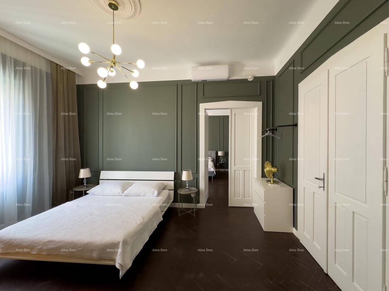 Helles Schlafzimmer mit dunklem Parkettboden, grünen Wandpaneelen und einem modernen Doppelbett.