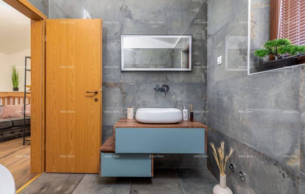 Modernes Badezimmer mit grauen Fliesen, stilvollem Waschbecken auf schwebendem Unterschrank und Holztür.