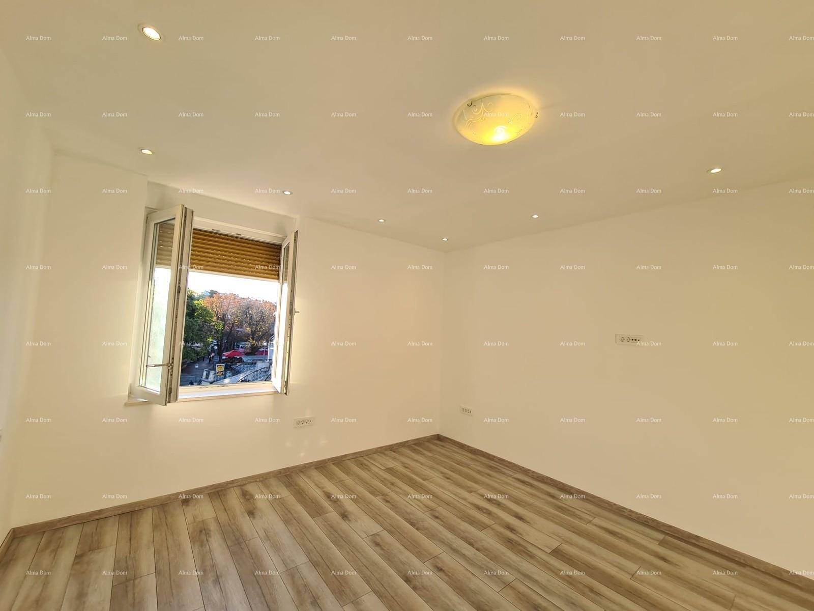 Helles Zimmer mit Holzoptik-Fliesenboden und einem Fenster mit Blick ins Grüne.